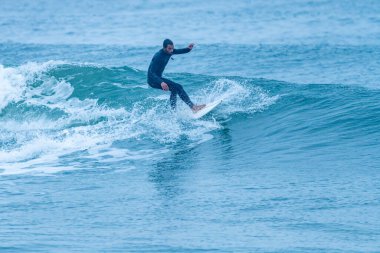 Sörfçü sisli bir sabahta sörf yapıyor Furadouro sahilinde, Ovar - Portekiz.