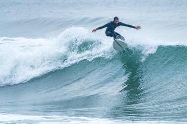 Sörfçü sisli bir sabahta sörf yapıyor Furadouro sahilinde, Ovar - Portekiz.