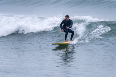Okyanus dalgalarında hareketli sörfçü bulutlu bir sabah Furadouro plajında, Ovar - Portekiz.