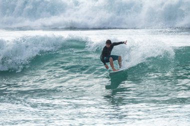 Portekiz 'in Furadouro plajında sörf yapan sörfçü. Okyanusta dalgaları yakalayan adamlar. Su sörfü sporu.