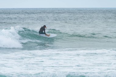 Portekiz 'in Furadouro plajında sörf yapan sörfçü. Okyanusta dalgaları yakalayan adamlar. Su sörfü sporu.