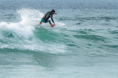 Portekiz 'in Furadouro plajında sörf yapan sörfçü. Okyanusta dalgaları yakalayan adamlar. Su sörfü sporu.