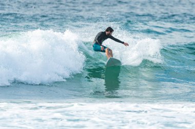 Portekiz 'in Furadouro plajında sörf yapan sörfçü. Okyanusta dalgaları yakalayan adamlar. Su sörfü sporu.