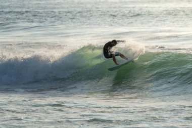 Portekiz 'in Furadouro plajında sörf yapan sörfçü. Okyanusta dalgaları yakalayan adamlar. Su sörfü sporu.