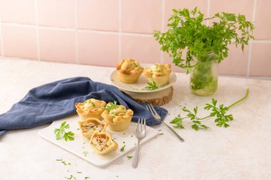 Tavuklu turtalar ve maydanoz yaprakları mutfak tezgahında beyaz seramik tabaklarda.