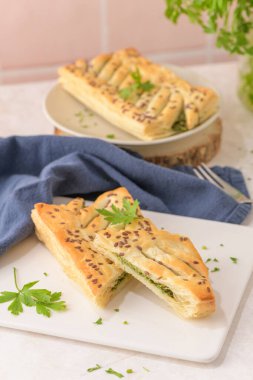 Ispanaklı puf böreği, ricotta peyniri ve maydanoz yapraklarıyla mutfak tezgahındaki beyaz seramik tabaklarda..