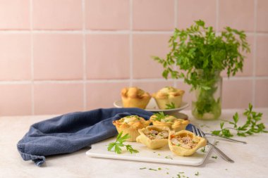 Tavuklu turtalar ve maydanoz yaprakları mutfak tezgahında beyaz seramik tabaklarda.