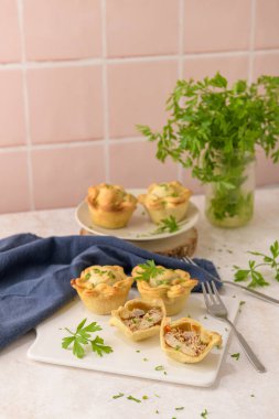 Tavuklu turtalar ve maydanoz yaprakları mutfak tezgahında beyaz seramik tabaklarda.