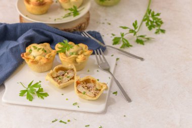 Tavuklu turtalar ve maydanoz yaprakları mutfak tezgahında beyaz seramik tabaklarda.