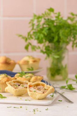 Tavuklu turtalar ve maydanoz yaprakları mutfak tezgahında beyaz seramik tabaklarda.