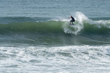 Portekiz 'in Furadouro plajında sörf yapan sörfçü. Okyanusta dalgaları yakalayan adamlar. Su sörfü sporu.