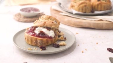 Çilek reçelli çörekler ve beyaz mutfak tezgahında cam şişede servis edilen sütlü pıhtılaşmış krema..