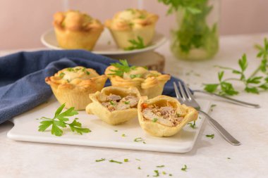 Tavuklu turtalar ve maydanoz yaprakları mutfak tezgahında beyaz seramik tabaklarda.