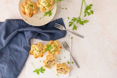 Tavuklu turtalar ve maydanoz yaprakları mutfak tezgahında beyaz seramik tabaklarda.