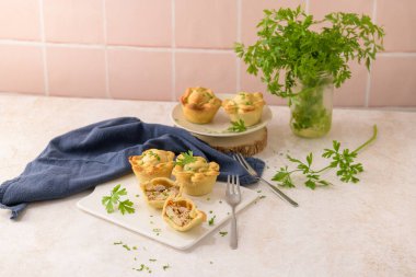 Tavuklu turtalar ve maydanoz yaprakları mutfak tezgahında beyaz seramik tabaklarda.