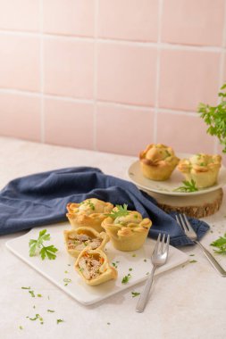 Tavuklu turtalar ve maydanoz yaprakları mutfak tezgahında beyaz seramik tabaklarda.