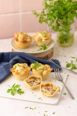 Tavuklu turtalar ve maydanoz yaprakları mutfak tezgahında beyaz seramik tabaklarda.