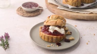 Çilek reçelli çörekler ve beyaz mutfak tezgahında cam şişede servis edilen sütlü pıhtılaşmış krema..