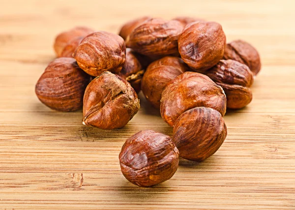 A pile of shell-less hazelnuts, isolated on textural wood backgr — Stock Photo, Image