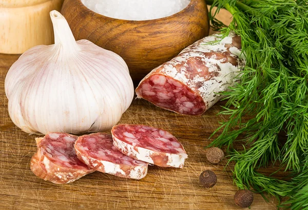 Salame fatiado na tábua de corte, com endro, pimenta, sal — Fotografia de Stock