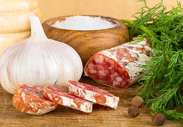 Rebanadas de salame en la tabla de cortar, con eneldo, pimienta, sal —  Fotos de Stock