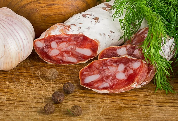 Rebanadas de salame en la tabla de cortar, con eneldo y pimienta — Foto de Stock