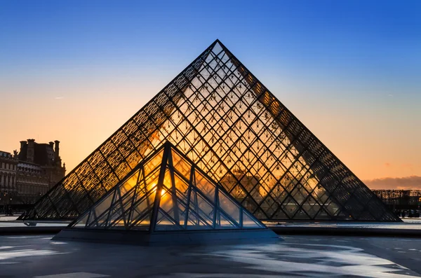 Sunset shines through the glass pyramid of the Louvre museum — Stock Photo, Image