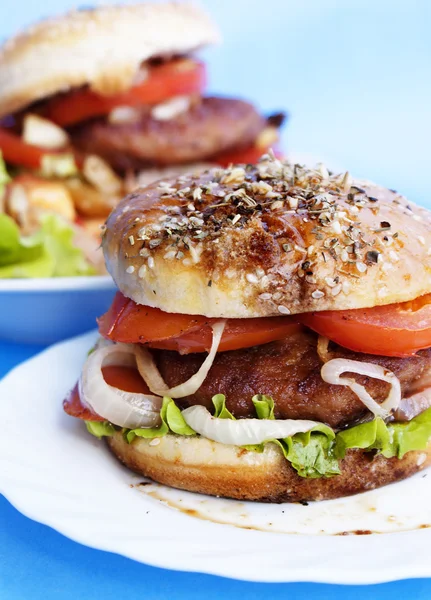 Burger s masem a pečená zelenina na modrém pozadí — Stock fotografie