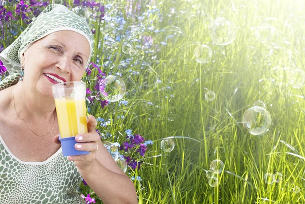 Mulher adulta com suco de laranja fresco de vidro em uma natureza — Fotografia de Stock