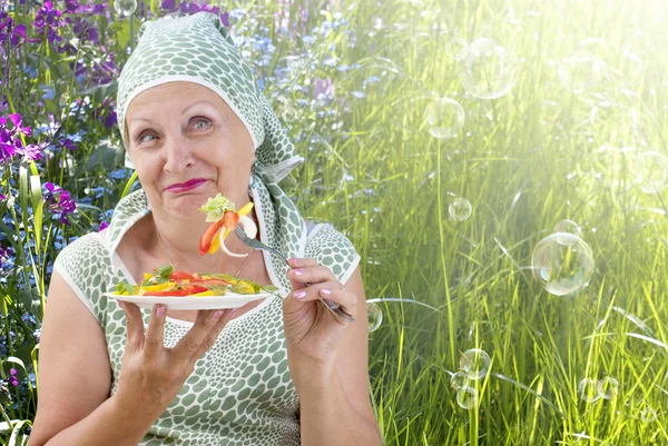 Volwassen vrouwtje verse plantaardige salade eten op een natuur — Stockfoto