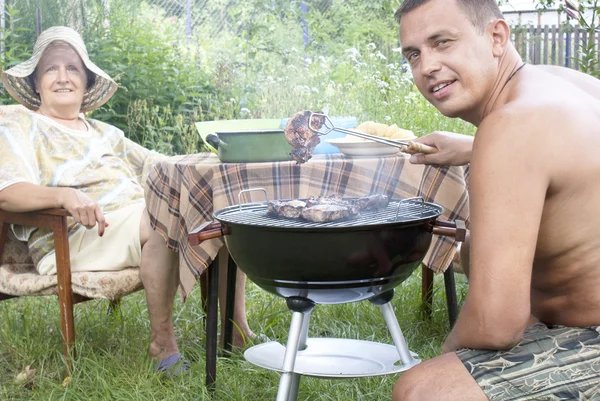 Happy family preparing a barbecue in the summer garden — Stock Photo, Image