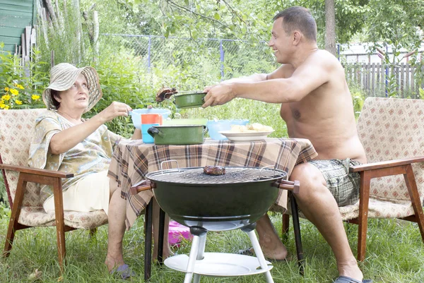 Família feliz preparando um churrasco no jardim de verão — Fotografia de Stock