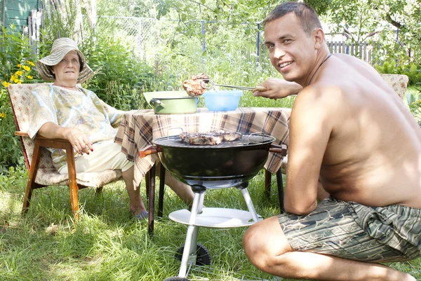 Happy family preparing a barbecue in the summer garden — Stock Photo, Image