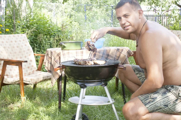 Adult man preparing a barbecue in the summer garden — Stock Photo, Image