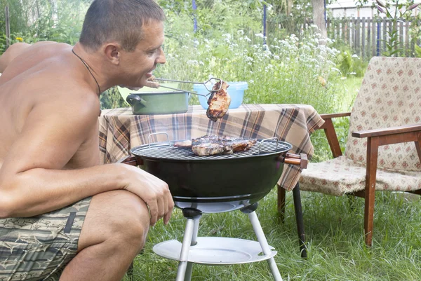 Adult man preparing a barbecue in the summer garden — Stock Photo, Image