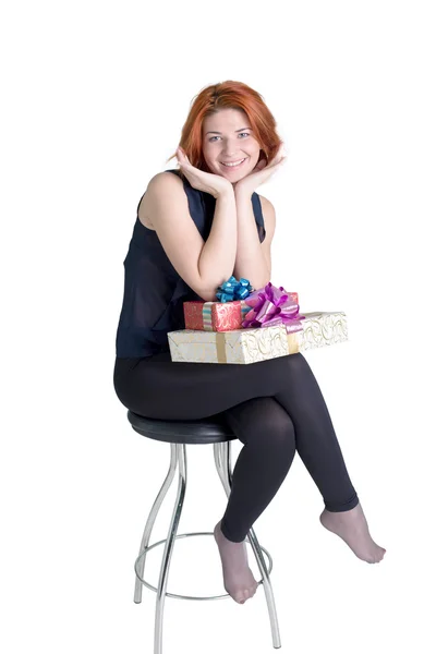 Menina alegre em uma cadeira com caixas presentes em um fundo branco — Fotografia de Stock