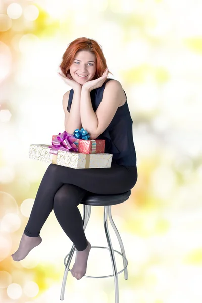 Joyful girl on a chair with boxes gifts — Stock Photo, Image