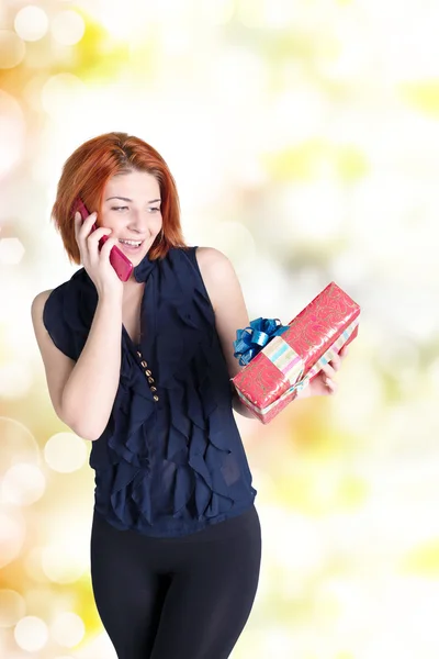 Glückliches Mädchen mit einem Telefon und einem Geschenk — Stockfoto