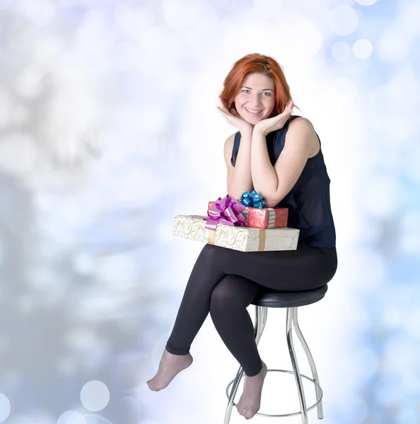 Chica alegre en una silla con cajas regalos.Vacaciones Año Nuevo y Navidad —  Fotos de Stock