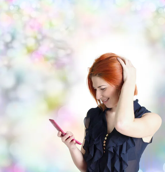 Chica emocional con el pelo rojo y un teléfono en el fondo festivo abstracto —  Fotos de Stock