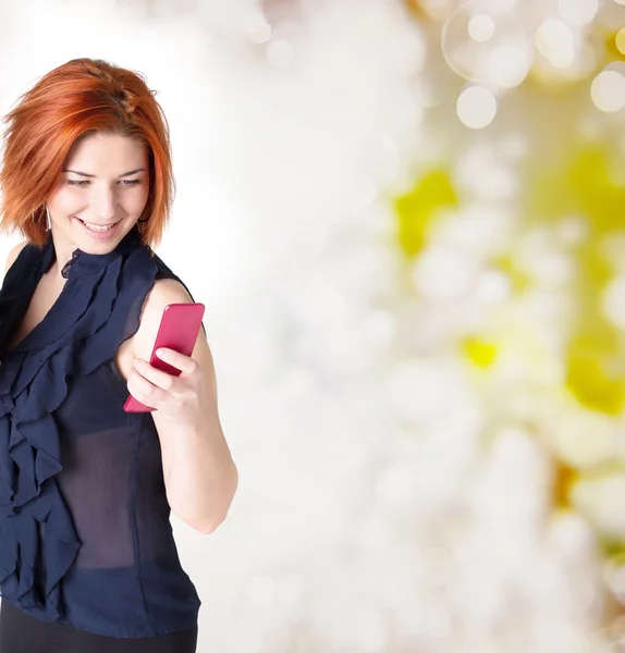 Donna felice emotiva con i capelli rossi e un telefono sullo sfondo festivo astratto — Foto Stock