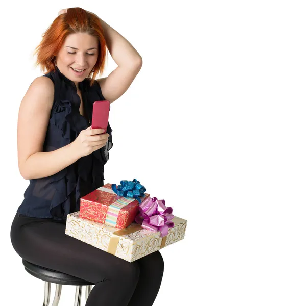 Mujer pelirroja feliz con una caja de regalo y un teléfono en el fondo blanco —  Fotos de Stock