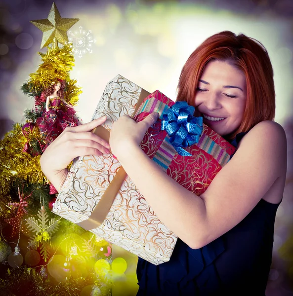 Joyeux sourire femme aux cheveux roux avec des boîtes cadeaux au sapin de Noël — Photo