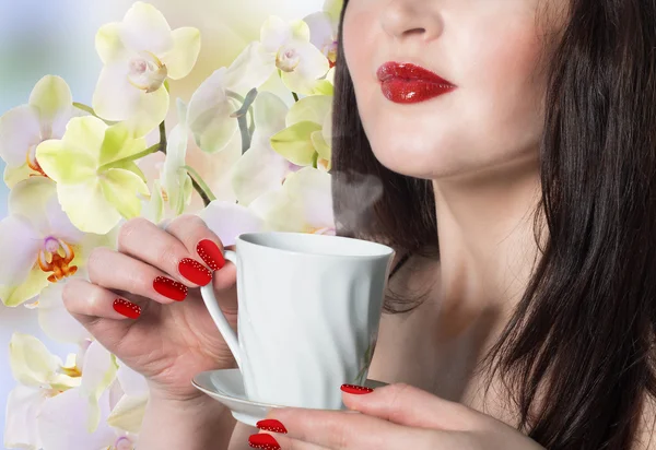 Giapponese bella ragazza con una tazza di tè verde germogli di orchidee. — Foto Stock