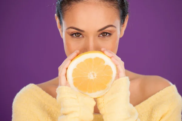 Mulher encantadora segurando uma laranja cortada pela metade — Fotografia de Stock