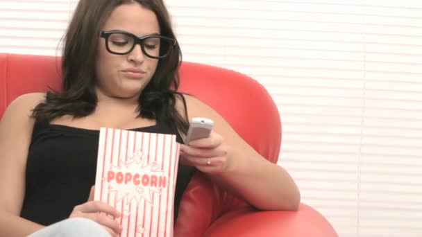 Chica joven en un sillón viendo una película — Vídeo de stock