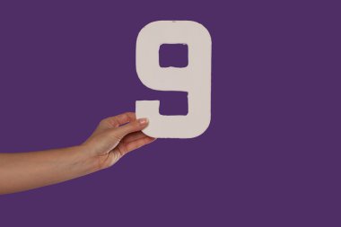 mujer mano sosteniendo el número 9 de la izquierda
