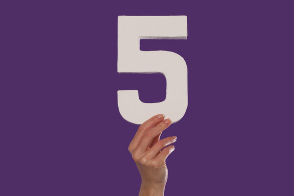 Female hand holding up the number 5 from the bottom