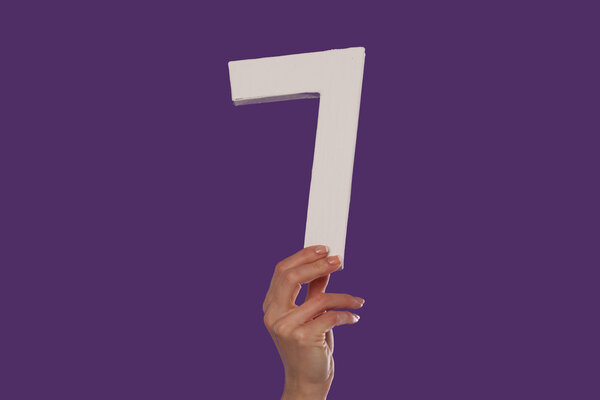 Female hand holding up the number 7 from the bottom