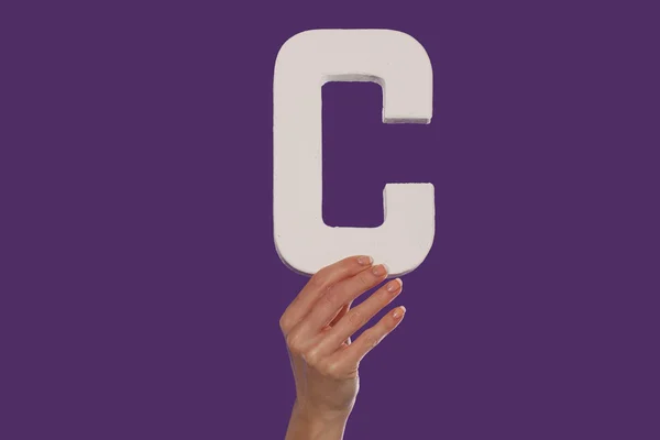 Γυναικείο χέρι που κρατά ψηλά το γράμμα c από το κάτω μέρος — Φωτογραφία Αρχείου
